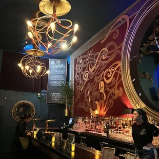 a bar with a large mirror and chandelier