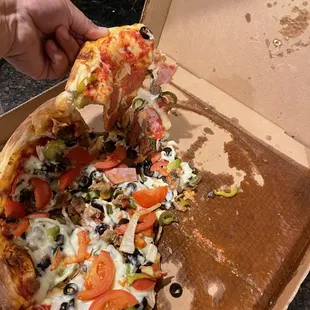 a person taking a slice of pizza