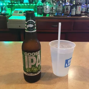 a bottle of boose ipa next to a plastic cup