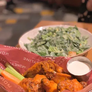 a plate of buffalo wings and a bowl of salad