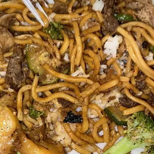 a plate of noodles and meat with broccoli