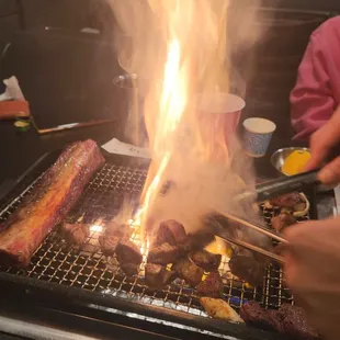 a person cooking a steak on a grill