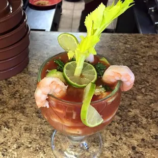 a bloody drink with shrimp and celery garnish
