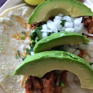 a taco with meat, onions, and avocado