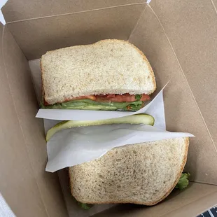 Sandwich to go - avocado, herb cream cheese, lettuce and tomato on fresh bread.