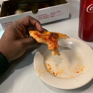 a hand holding a slice of pizza