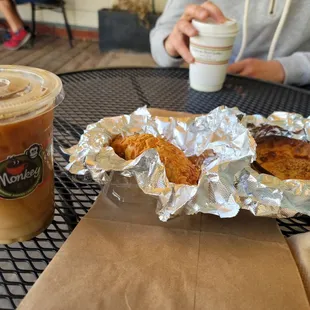 a person sitting at a table with a sandwich and iced coffee