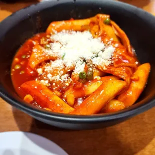 a bowl of pasta with sauce and parmesan cheese