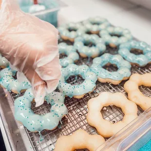 a person putting frosting on donuts