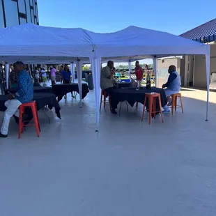 a group of people sitting at tables under a tent