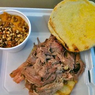 a pulled pork sandwich with a side of beans