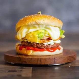 a hamburger with cheese, lettuce, tomato, and mayonnaise