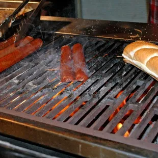 hot dogs and buns cooking on a grill