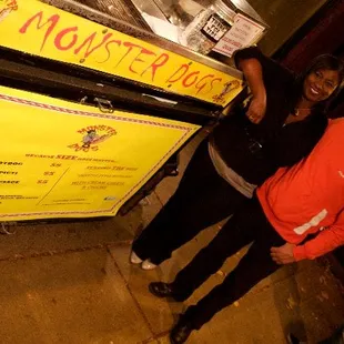 two people standing in front of a monster dog