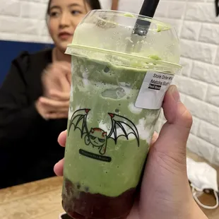 a hand holding a cup of green tea