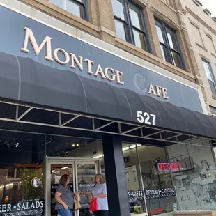 a couple of people walking in front of a restaurant