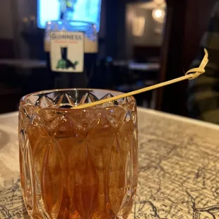 a glass of whiskey with a toothpick sticking out of it