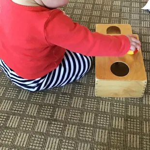 An infant friend using an object permanence box.