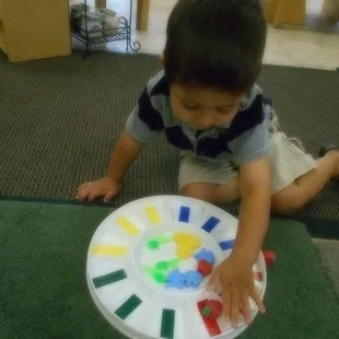 A toddler child sorts objects by color.