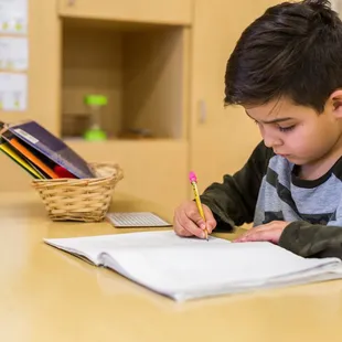 Montessori develops independence, focus, and a love of learning at an early age. This student is engrossed in his self-selected assignment.