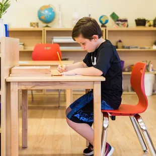 Montessori develops independence, focus, and a love of learning at an early age. This student is engrossed in his self-selected assignment.