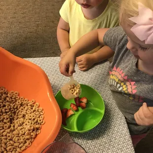Toddlers learn independence by serving themselves snack (under teacher supervision)