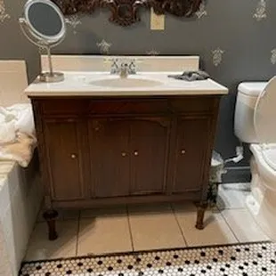 Vanity w/hair on wall and missing tile in front