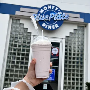 a hand holding a pink drink