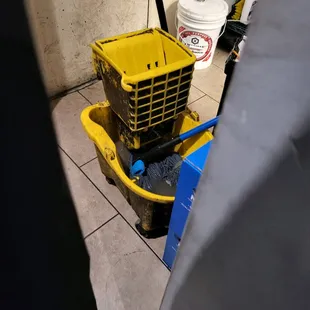 Standing Mop in Black Mop water near kitchen.