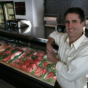 a man standing in front of a display of meat