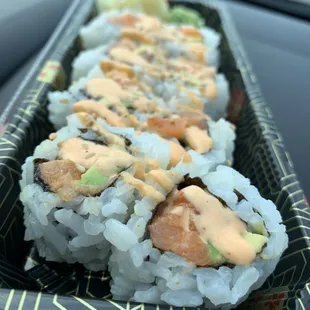 a hand holding a tray of sushi