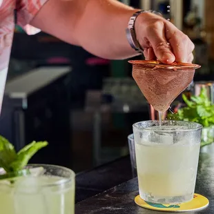 a bartender pouring a drink into a glass