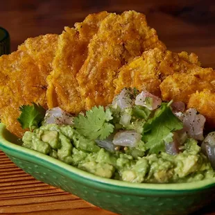 a green bowl of guacamole and onion chips