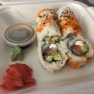 a close up of a sushi roll in a styrofoam container