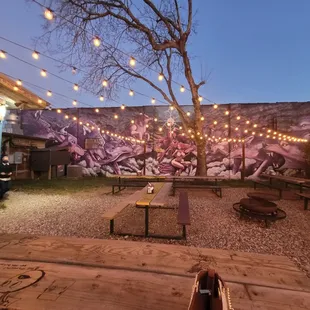 a patio area with tables, benches, and string lights