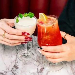 two people holding cocktails