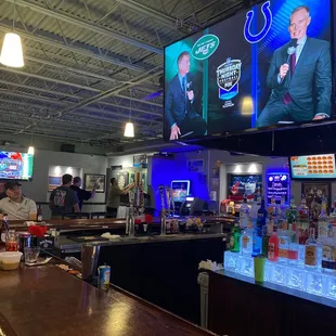 a man sitting at the bar watching tvs