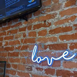 a brick wall with a neon sign that reads love