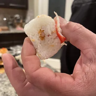 a hand holding a piece of sushi