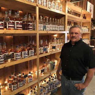 a man standing in front of a shelf of bottles