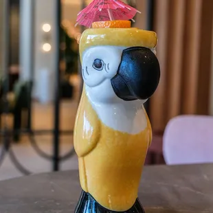 a yellow parrot with a pink umbrella