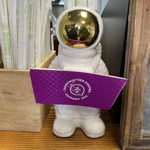 a white astronaut holding a purple sign