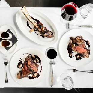 a table setting with steak, mushrooms, and wine