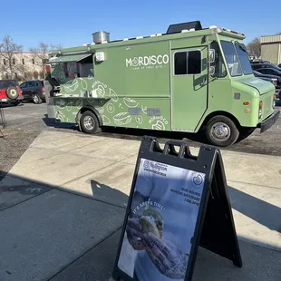 a green food truck parked in a parking lot