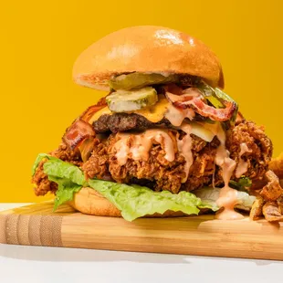Cluck N Chuck Sandwich. smashed burger patty with buttermilk chicken, cheese, lettuce,tomato, and pickles all on a brioche bun