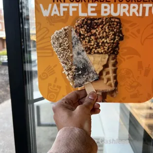 a hand holding a waffle burrito