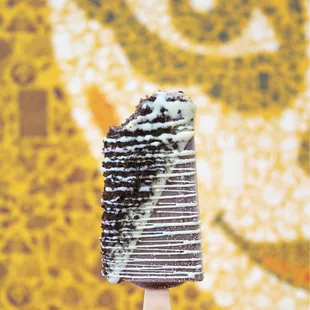 Chocolate Fudgy Brownie Paleta dipped in White Chocolate, topped with Oreo Cookie Crumbs, and drizzled with White Chocolate