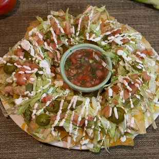 a plate of taco salad with a bowl of salsa