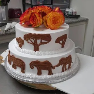a three tiered cake with elephants and flowers on top