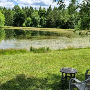 two chairs and a table in front of a pond